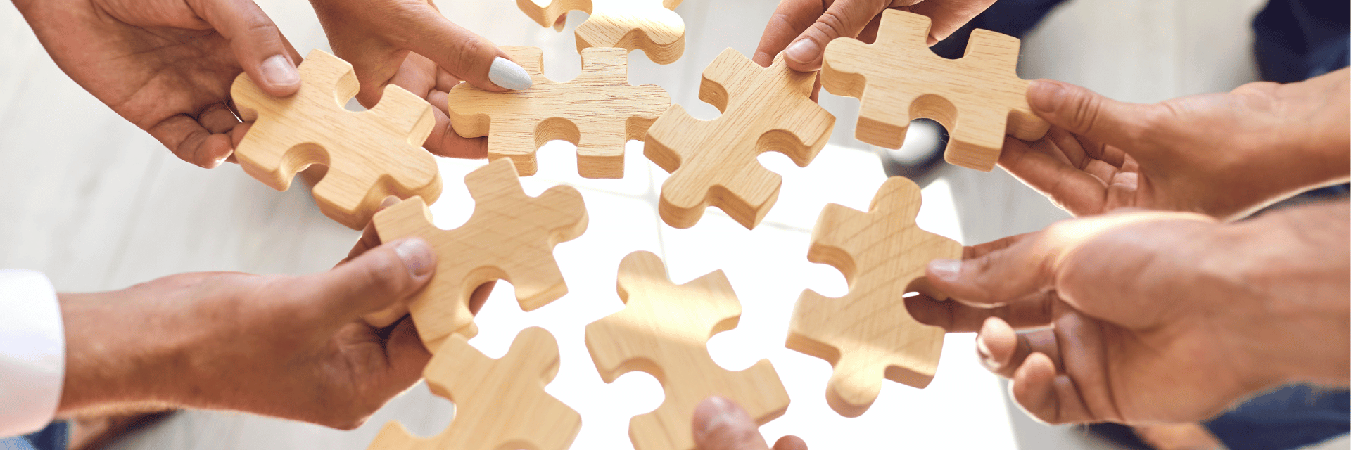 Mitarbeiter legen Puzzleteiele zusammen als Symbolbild für die Verwaltung mehrerer Unternehmen