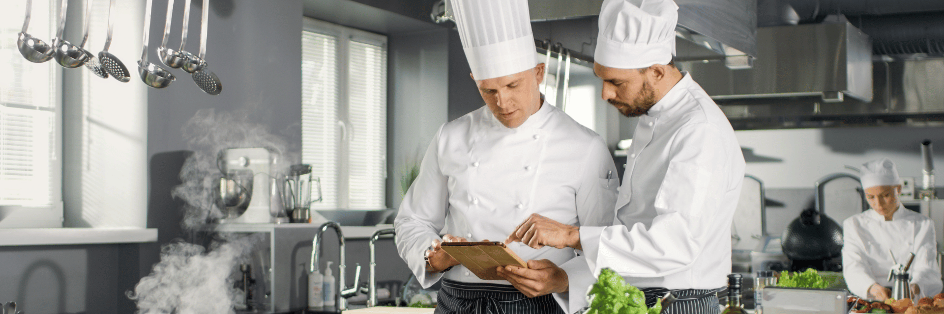 Zwei Köche in der Hotellerie geben Bestellungen über ein Tablet auf