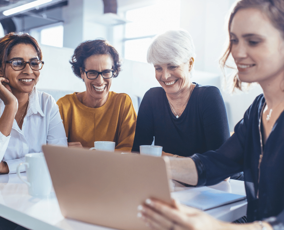 Fröhliches Team von vier Frauen in der Buchhaltung. Diskussion am Laptop.