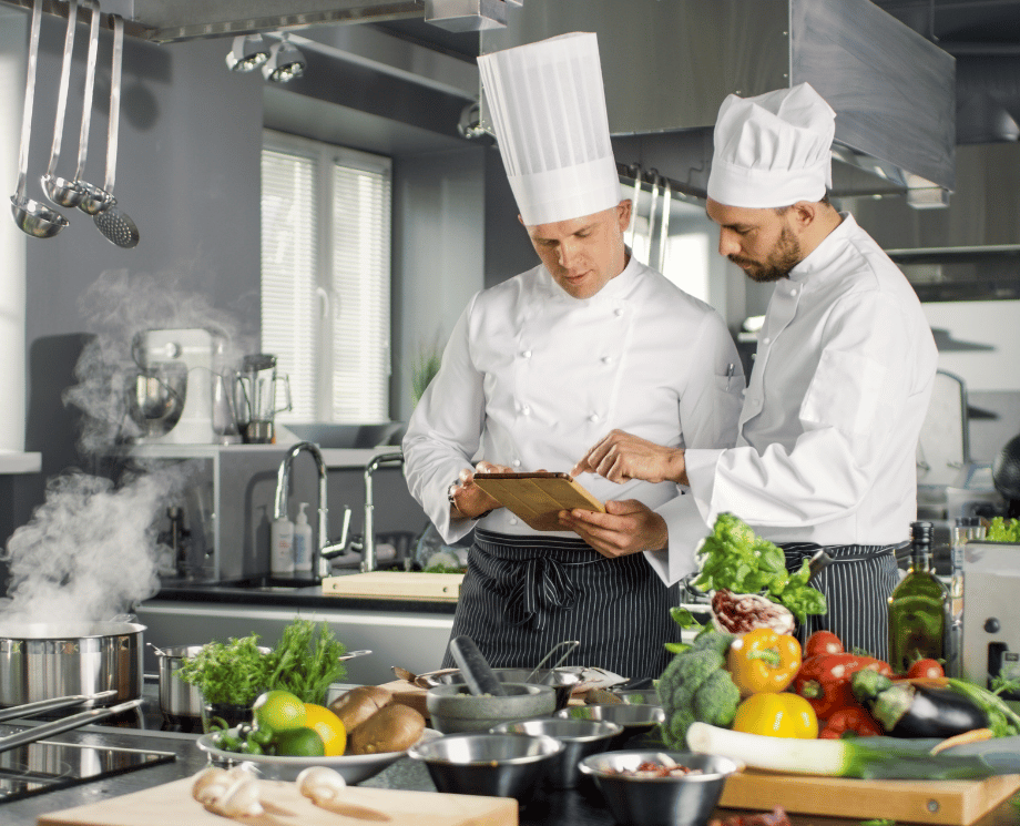 Zwei Köche im Hotel-Restaurant organisieren den Beschaffungsprozess per Tablet.