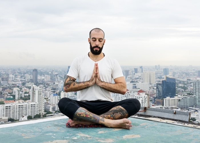 Mann in Yoga-Position auf einem Gebäude-Dach. Für dekorative Zwecke.