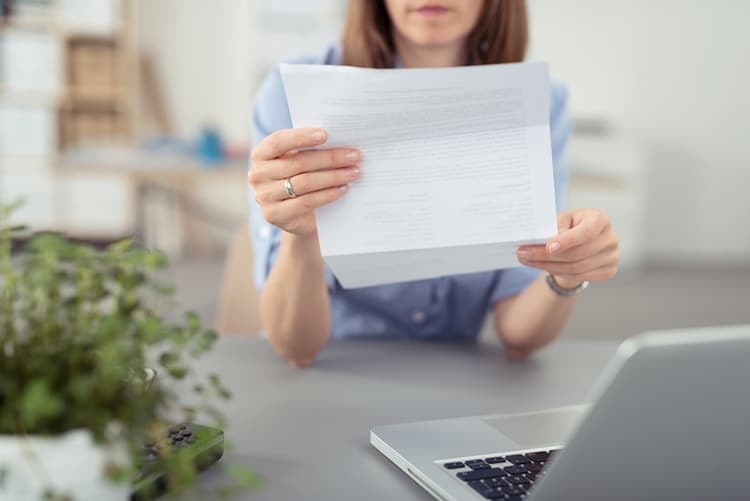 frau sitzt am schreibtisch und liest einen brief