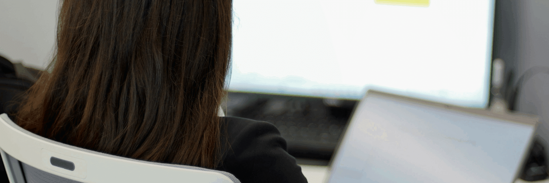 Eine Frau sitzt vor einem Laptop und hat ein Tabellenprogramm geöffnet